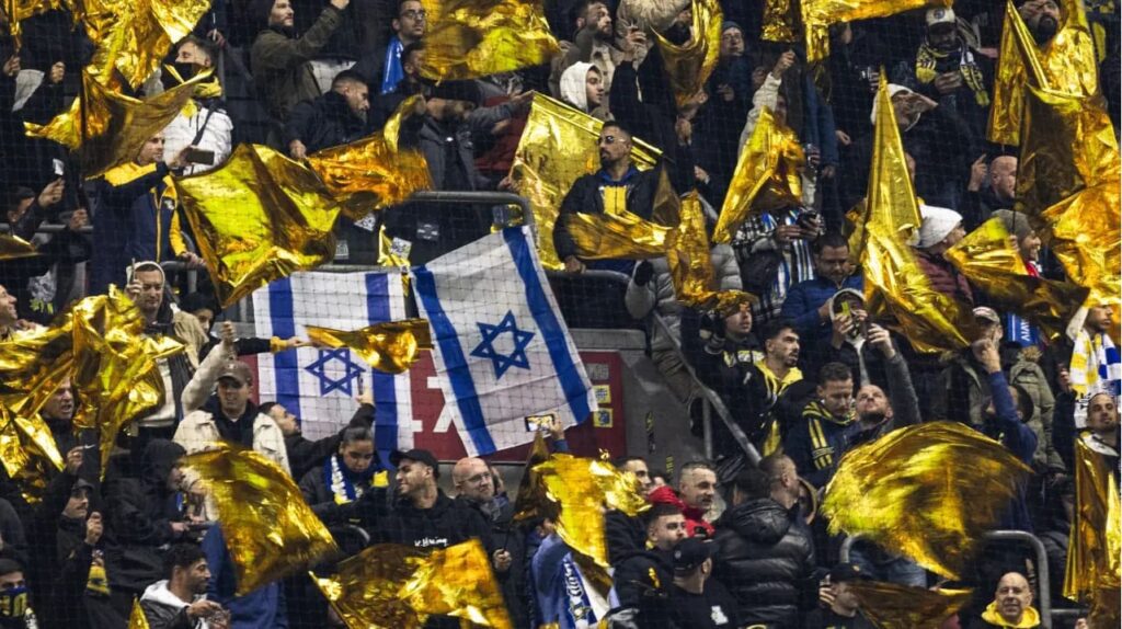 Torcedores do Maccabi agitam bandeiras amarelas ao lado de bandeiras israelenses durante a fase da Liga Europa da UEFA, em partida de futebol contra o Ajax Amsterdam. 07/11/2024 - (Robin van Lonkhuijs...